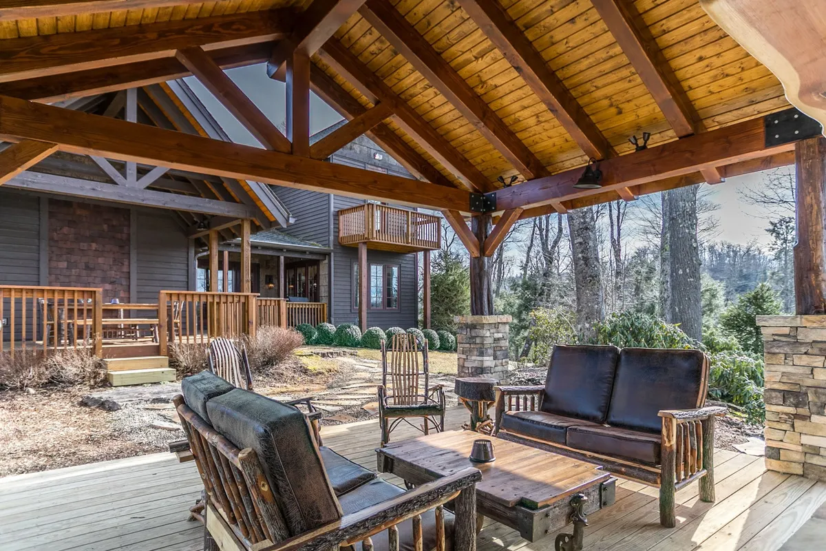 A rustic wooden gazebo with comfortable seating is nestled among lush greenery and stone accents. The setting offers a sheltered yet open space for relaxing outdoors, socializing, or enjoying nature in comfort, especially suited for gatherings or winding down after a day of adventure.