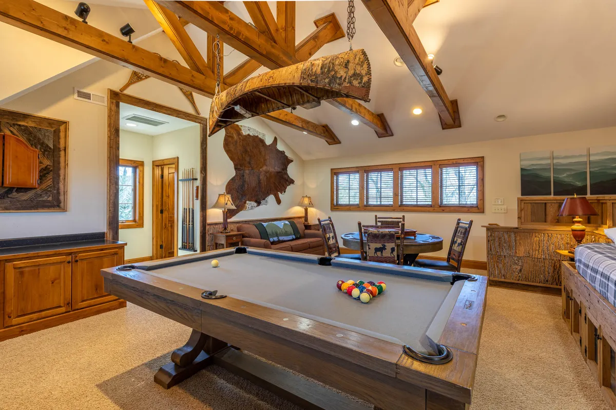 A spacious game and bunk room featuring a pool table, timber beams, a cozy sofa, and a dining area. The atmosphere is friendly and relaxed, with space for both fun and rest, ideal for multi-generational groups or children.